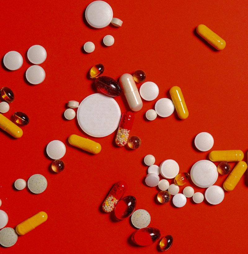 Different Medication Pills And Capsules on Red Background