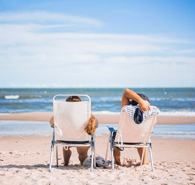 woman in black and white stripe dress sitting on white chair on beach during daytime