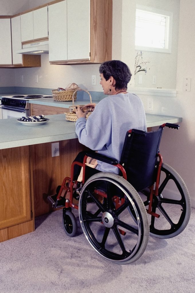 a woman in a wheel chair in a kitchen